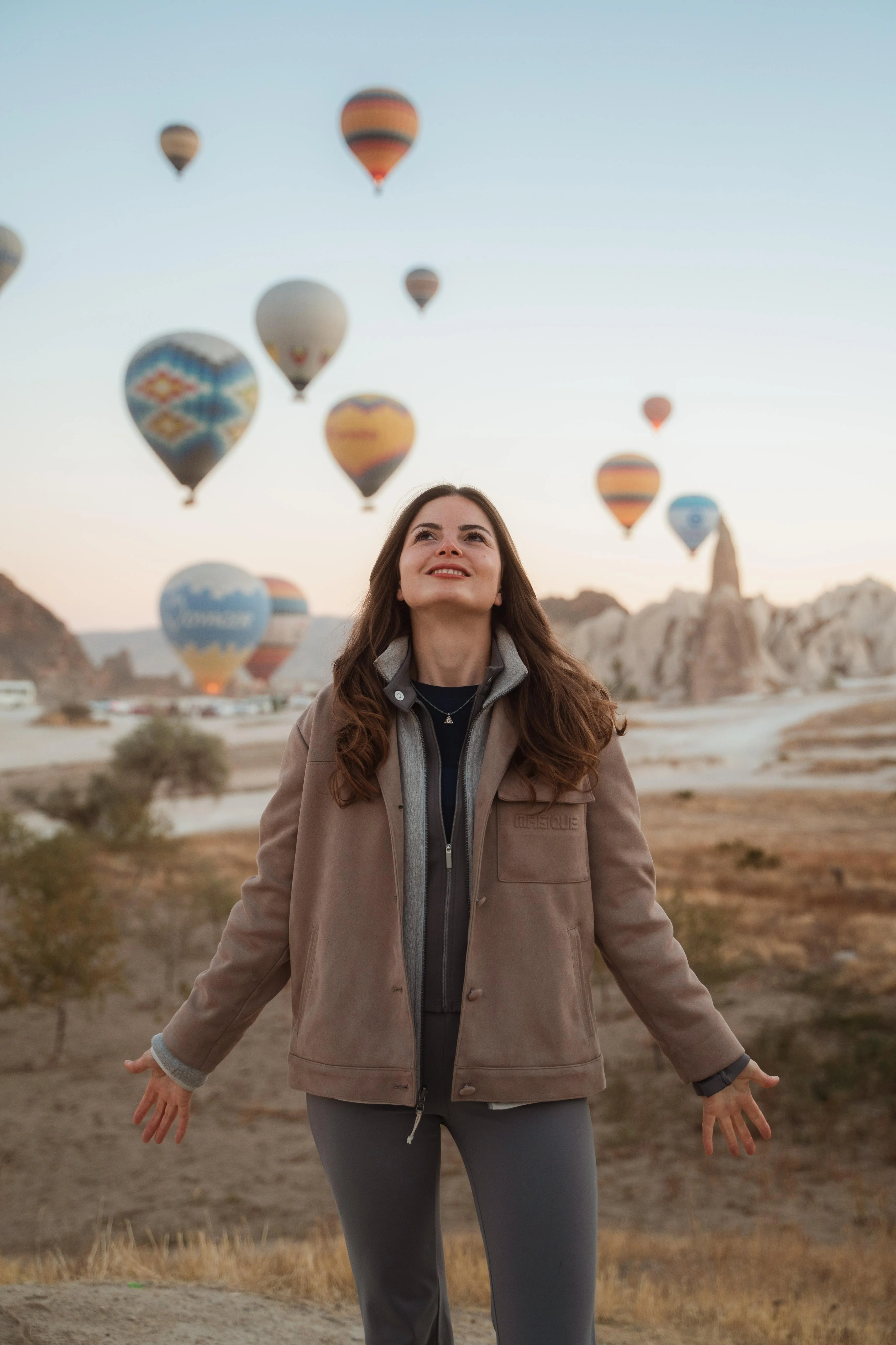 Selin mit ausgebreiteten Armen vor Heißluftballons in Kappadokien