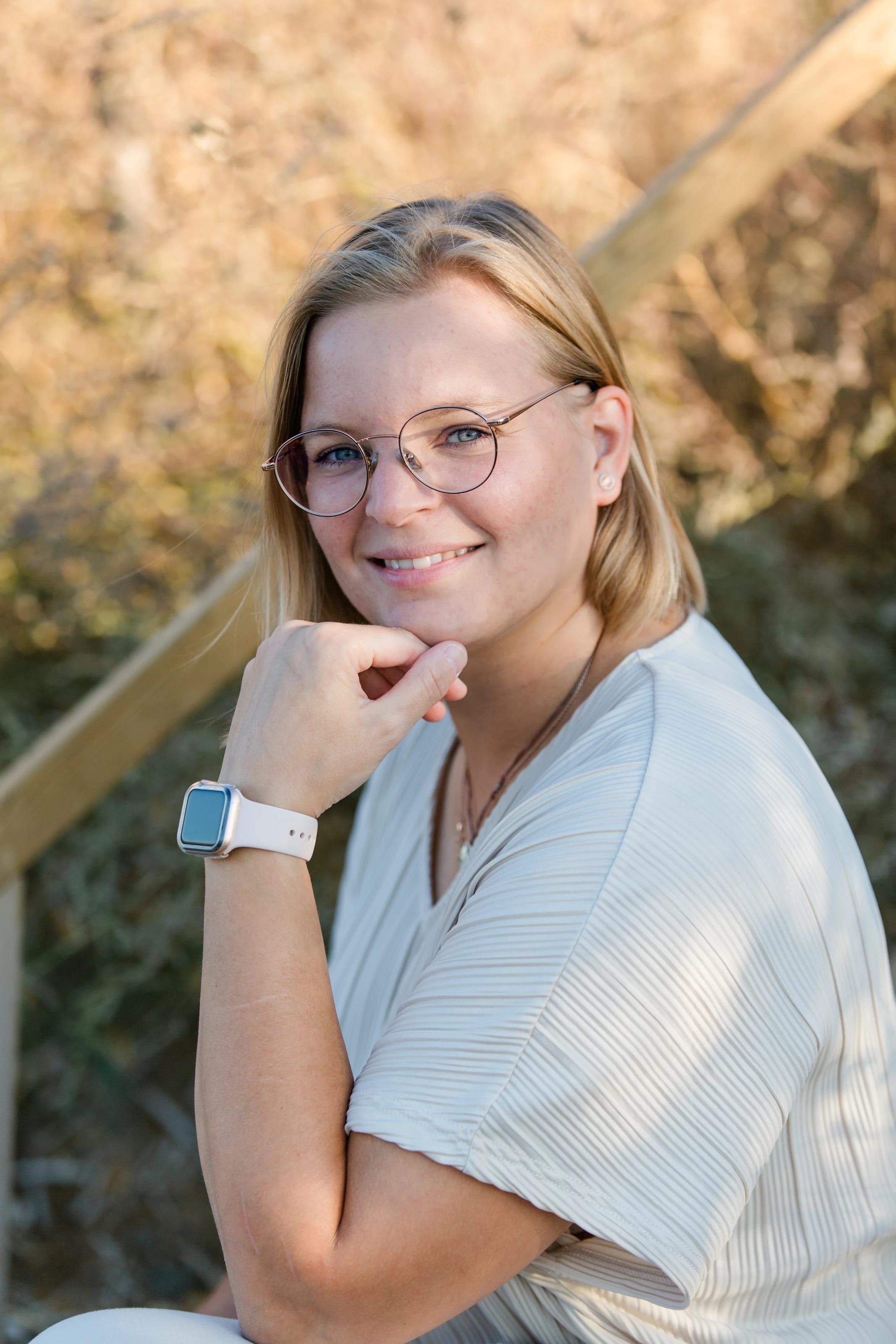 Jennifer lächelt in die Kamera, mit Brille, im hellen Oberteil