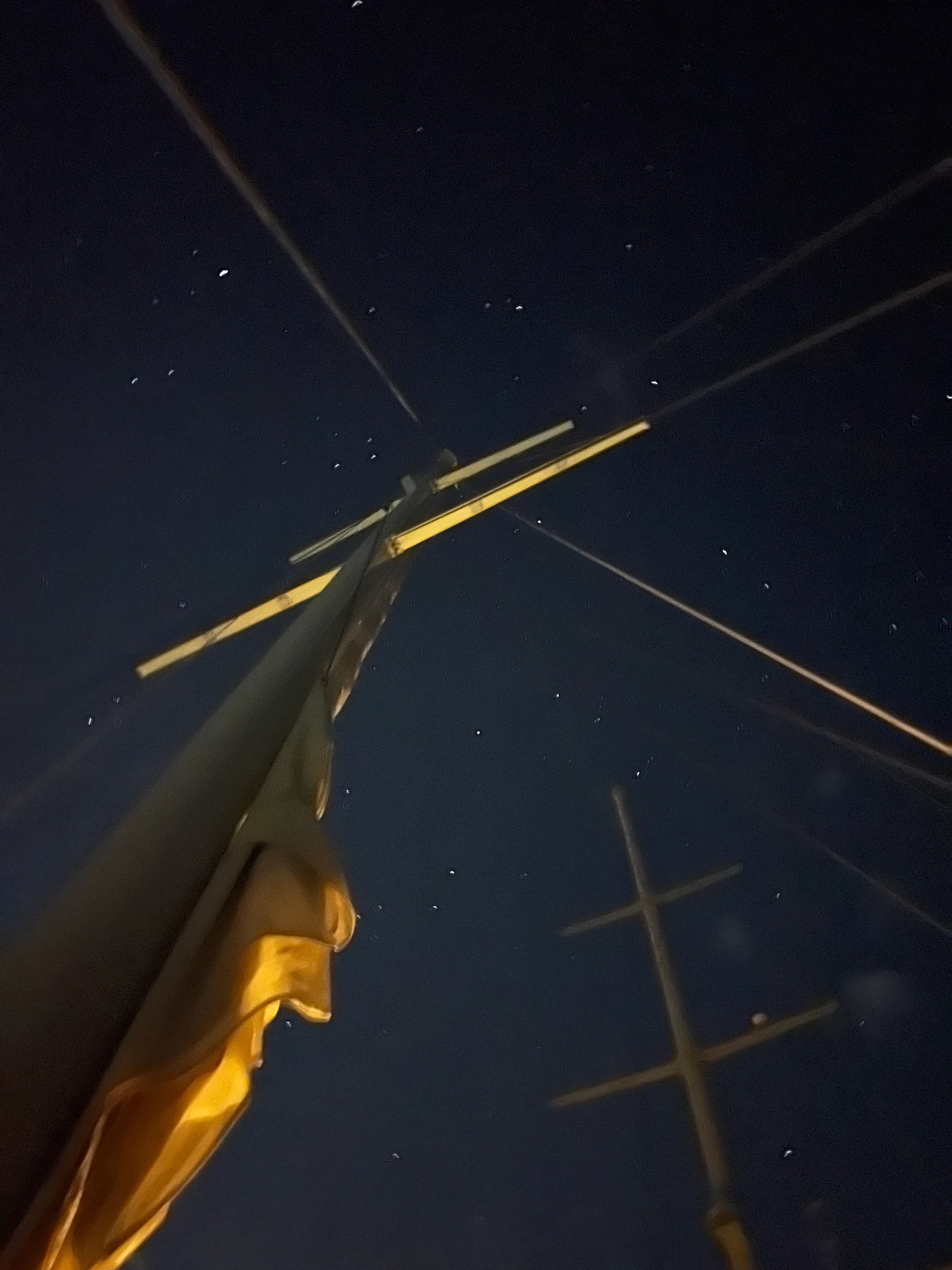 Sternenhimmel über dem beleuchteten Mast der Yacht bei Nacht.