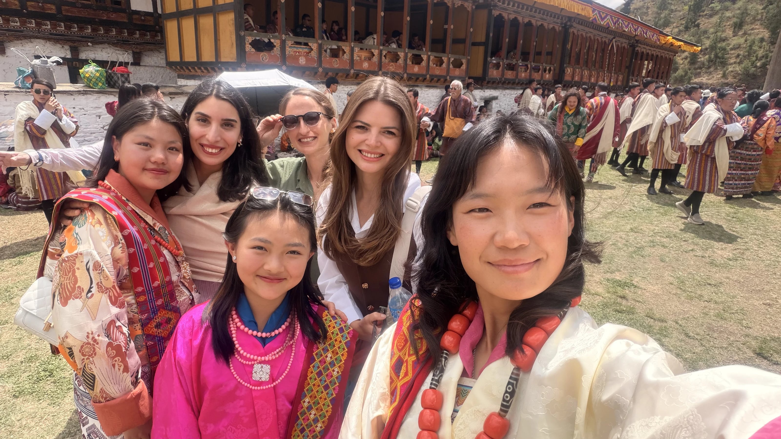 Reisegruppe macht ein Selfie mit bhutanischen Einheimischen bei einem traditionellen Fest.