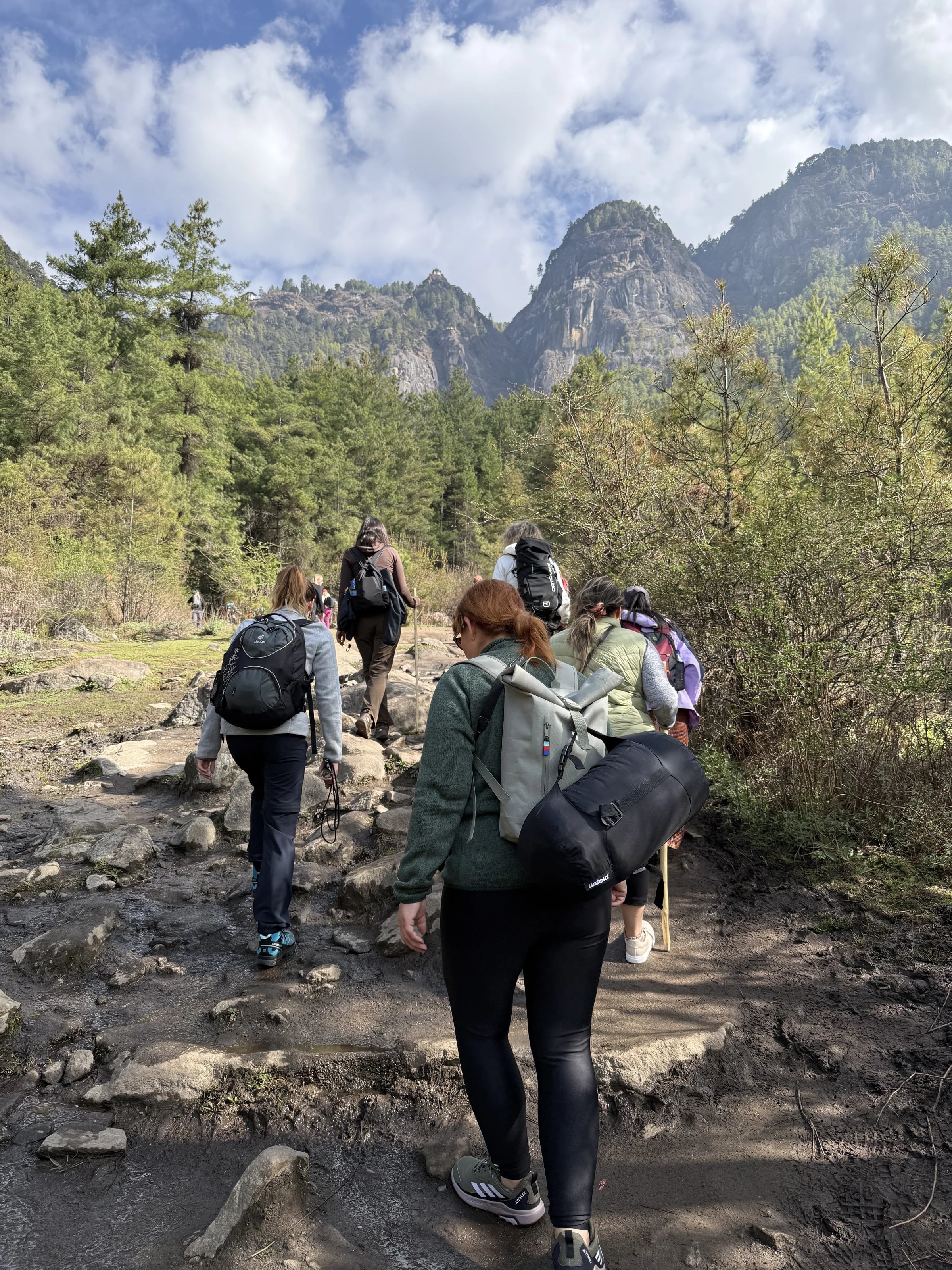 Wandergruppe steigt auf steinigem Pfad zum Kloster Taktsang (Tiger's Nest) hinauf.