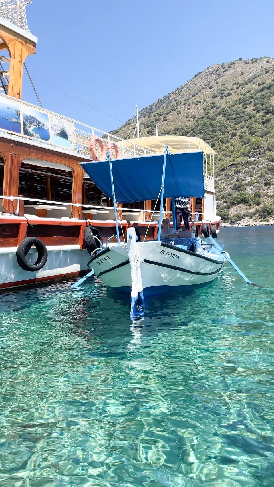 Ein kleines weißes Boot aus Fethiye liegt in glasklarem, türkisfarbenem Wasser.