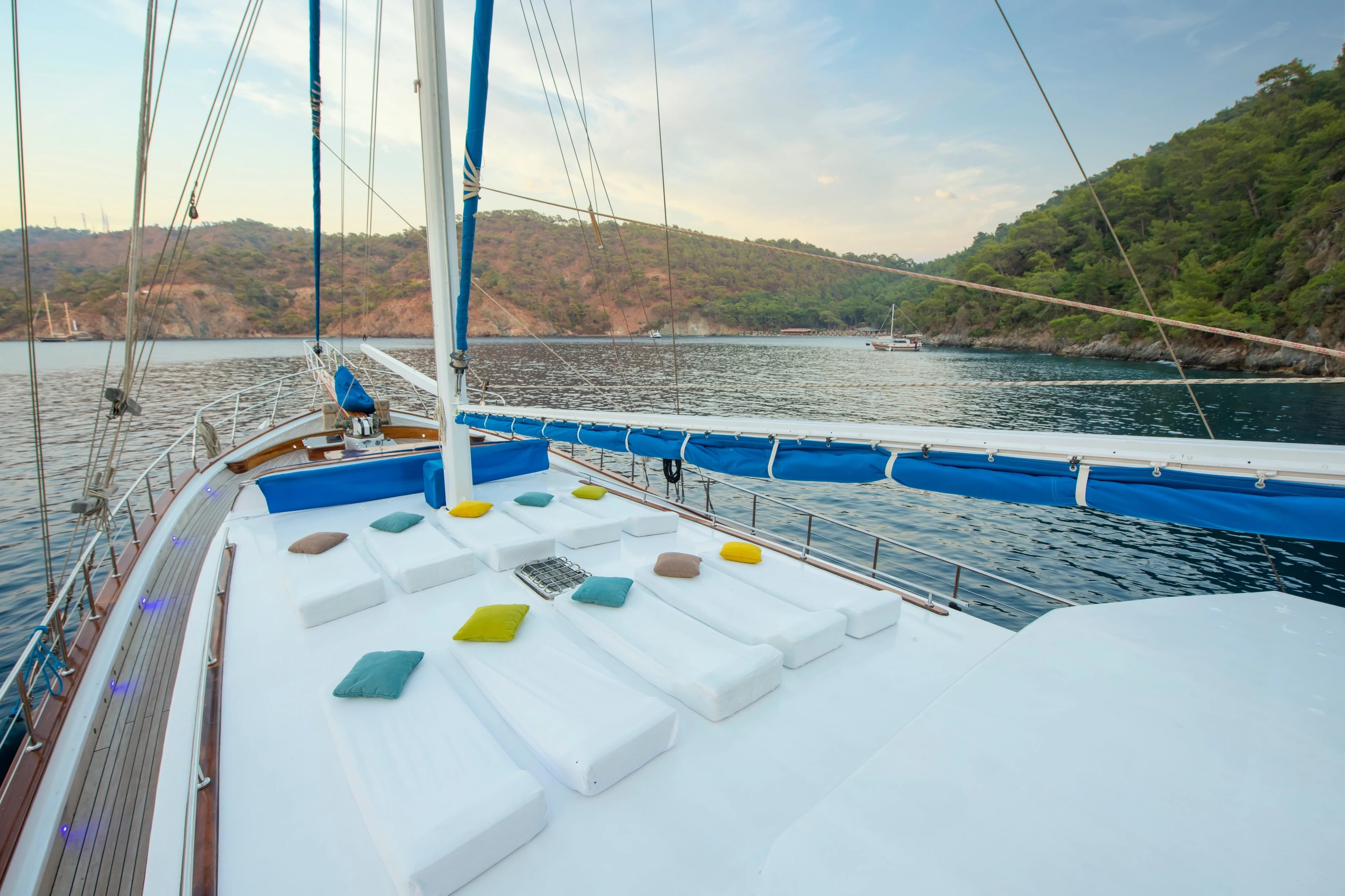 Das Sonnendeck der Northwind mit weißen Liegen und bunten Kissen, dahinter eine bewaldete Bucht im Abendlicht.