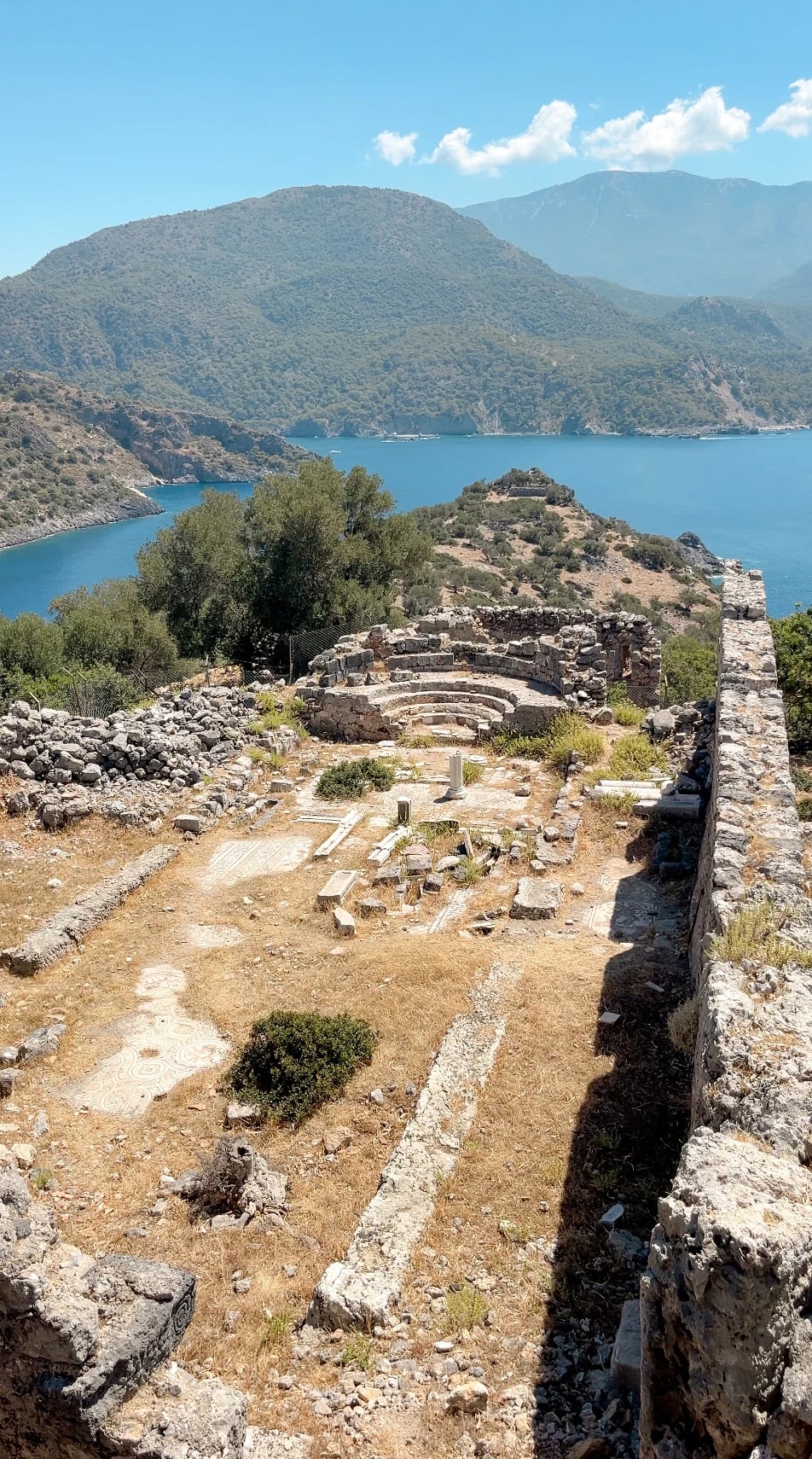 Byzantinische Ruinen mit Mosaikresten auf St. Nicholas Island, dahinter Meer und Berge.