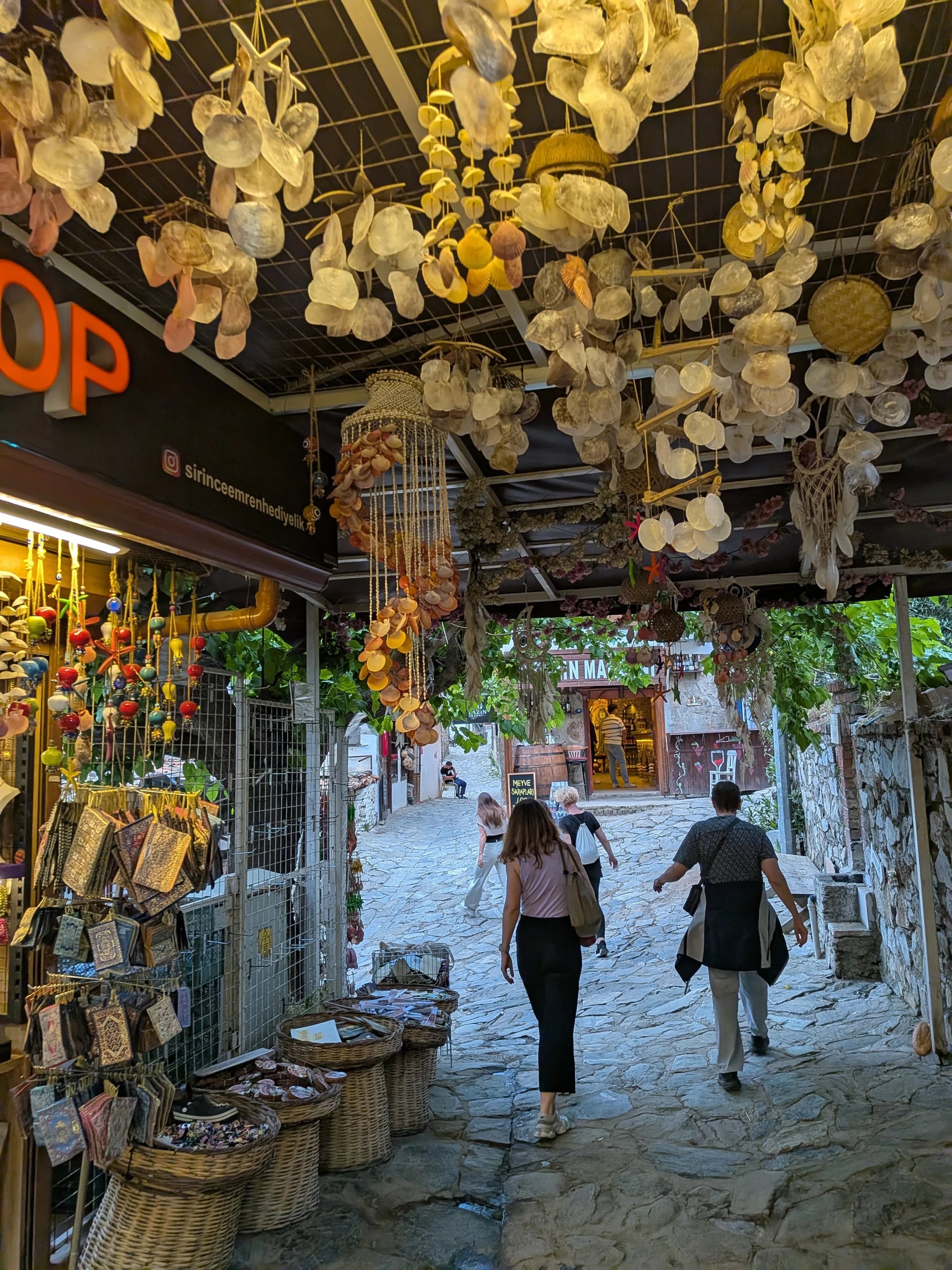 Eine Gasse in Şirince, über der getrocknete Blumen hängen, links und rechts Stände mit Waren.