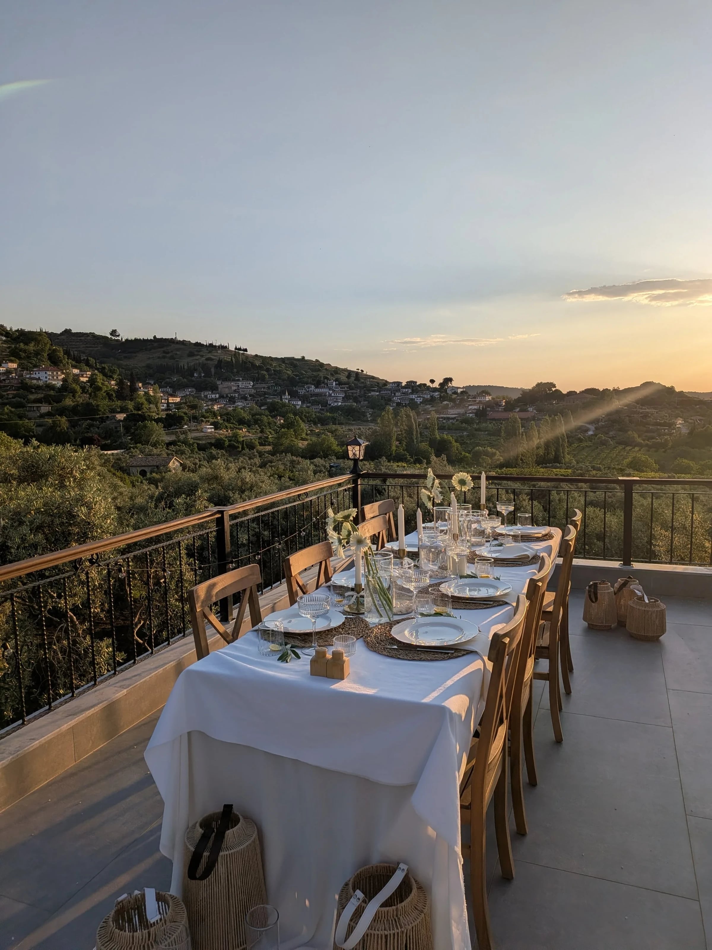 Weiß gedeckte Tafel auf einer Terrasse mit Weitblick über die Hügel im Abendlicht.