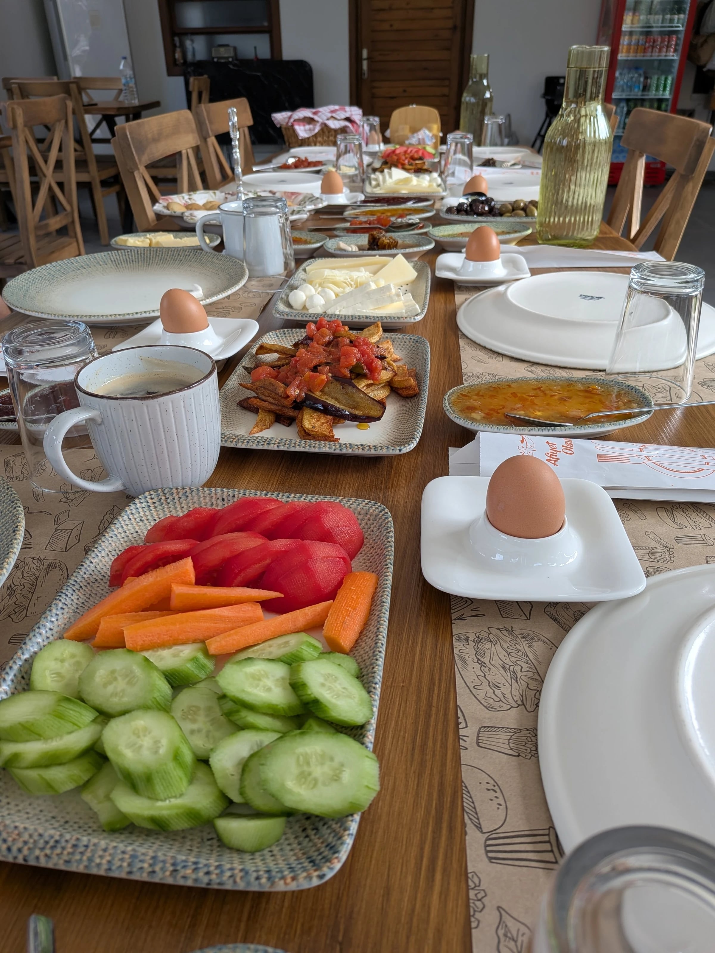 Reich gedeckter Frühstückstisch mit Gurken, Tomaten, Käse, Eiern und Tee.