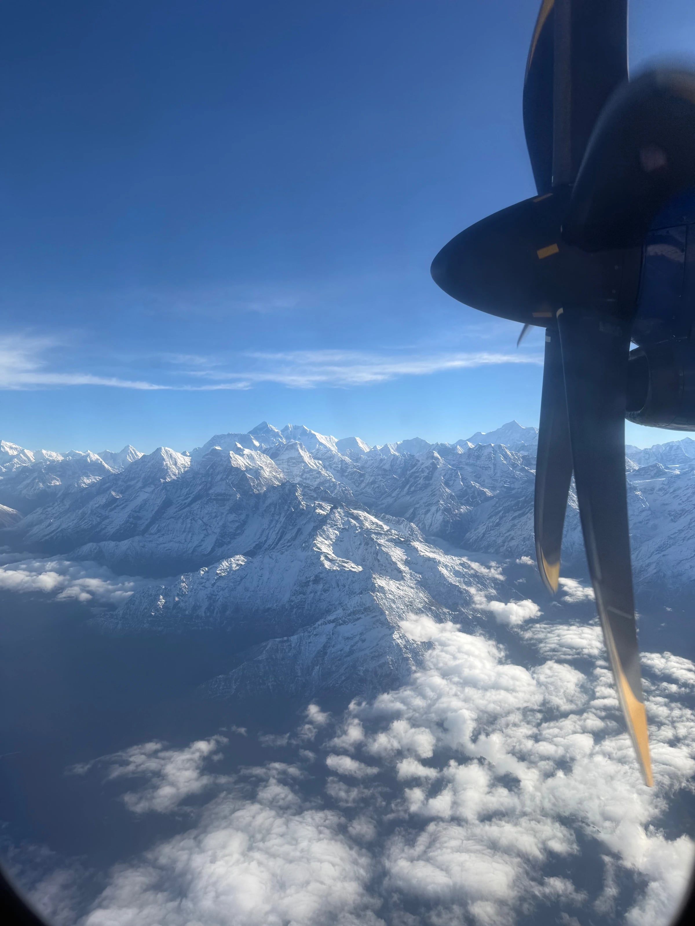 Blick aus dem Flugzeugfenster über schneebedeckte Achttausender im Himalaya während des Everest-Rundflugs.