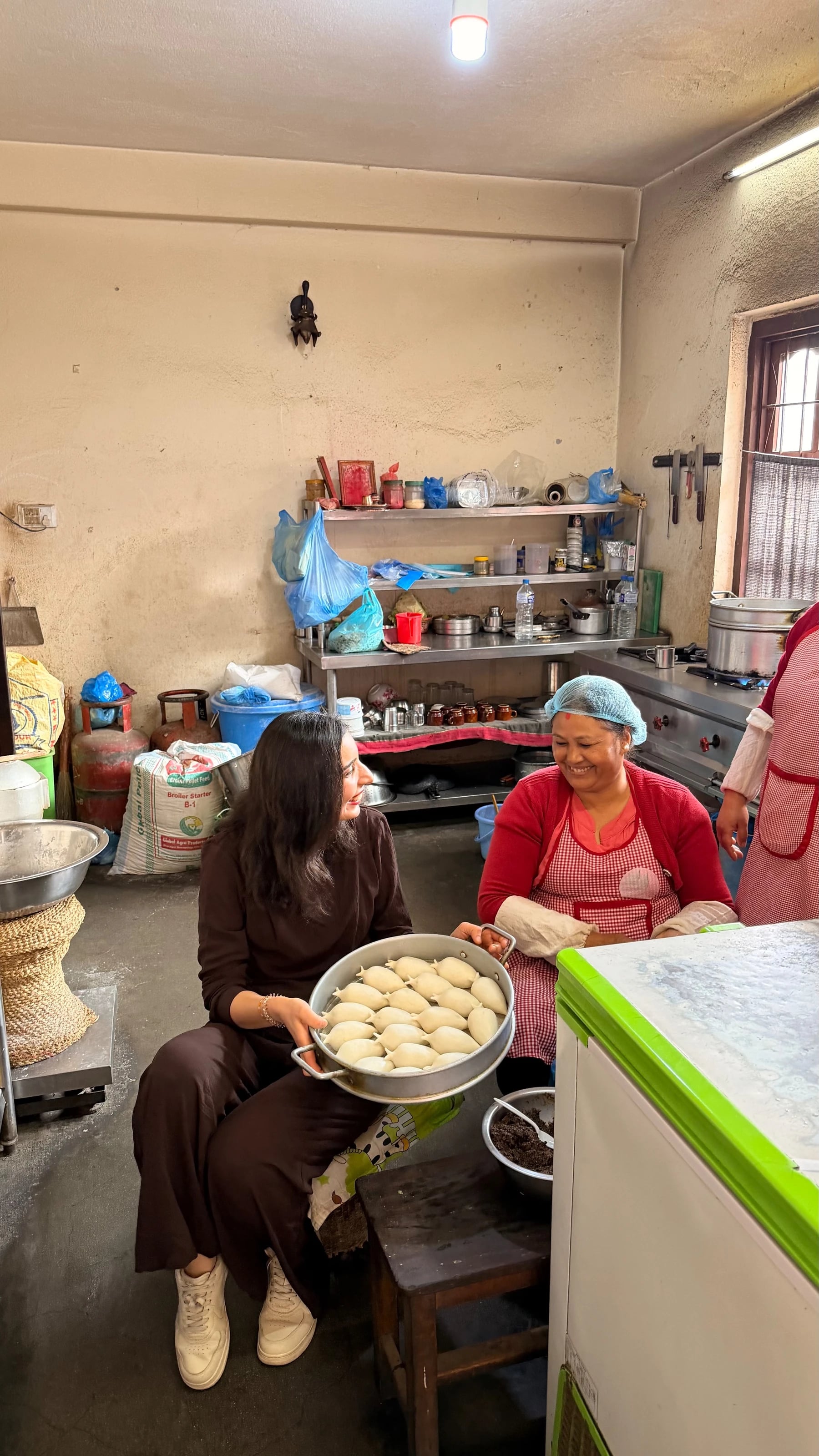 Eine Reisende hilft in einer Küche in Kathmandu beim Formen von Momos gemeinsam mit einer Köchin.