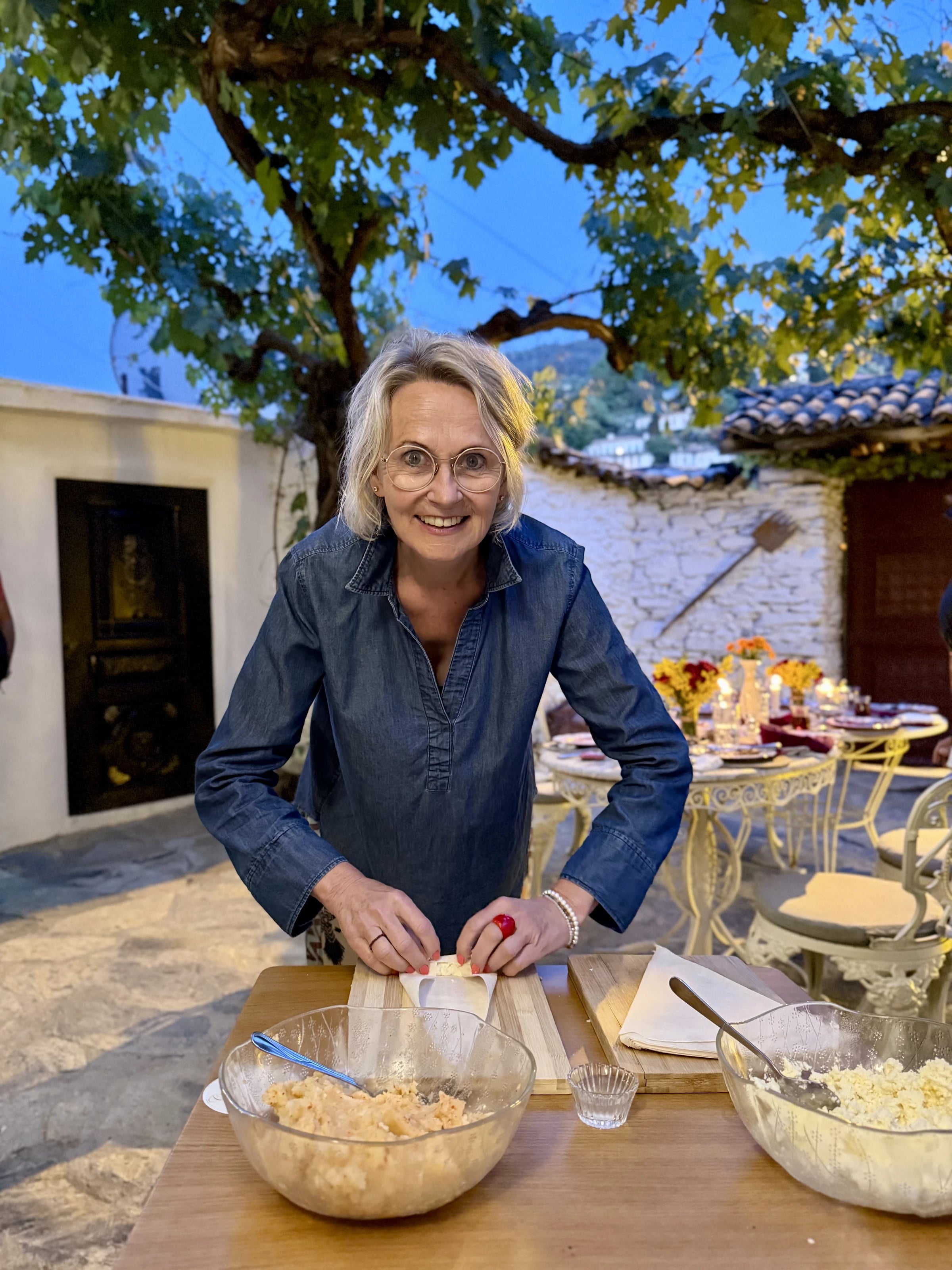Astrid rollt lachend Börek an einem Holztisch im abendlichen Innenhof.