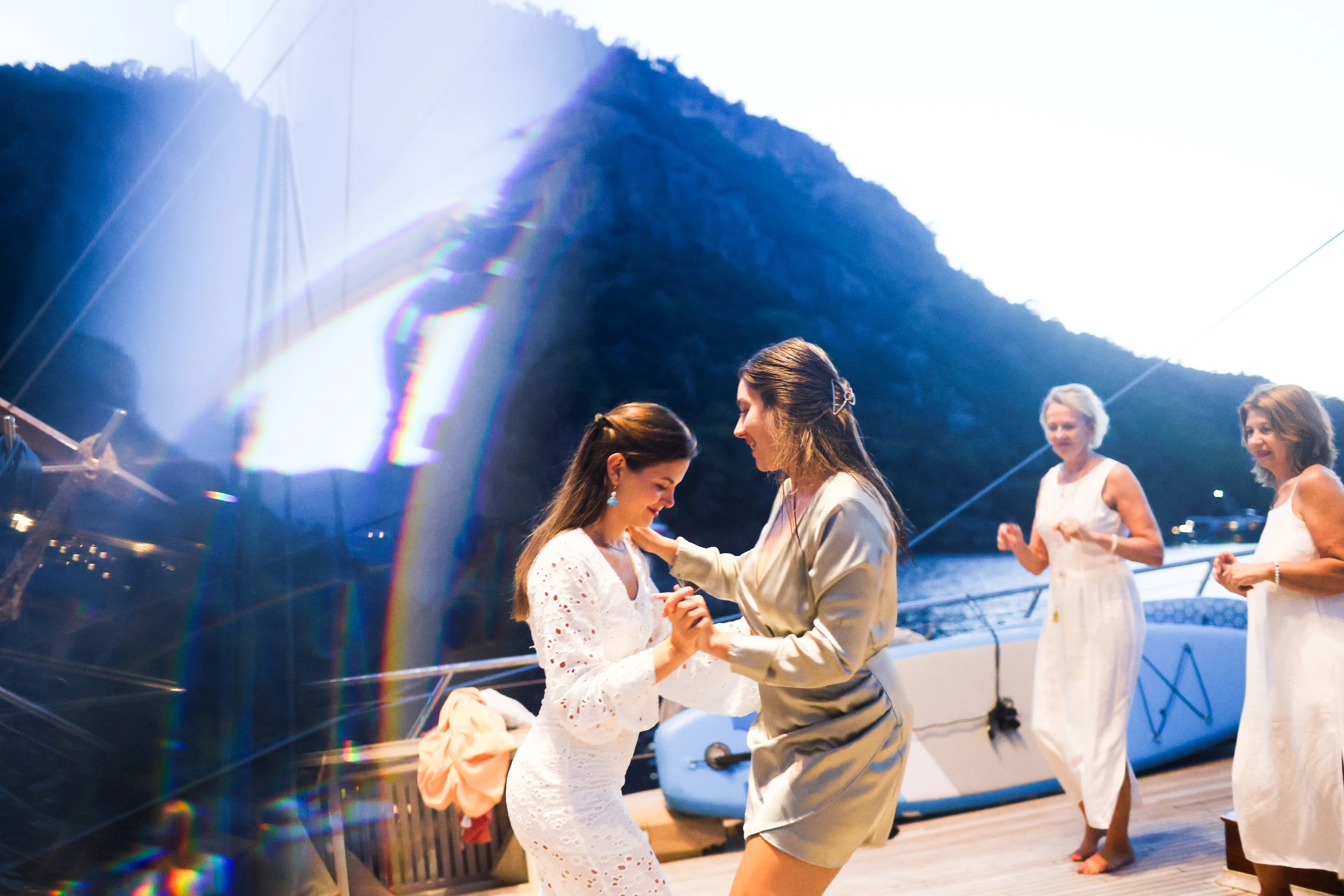 Zwei Frauen tanzen eng umschlungen bei Nacht an Deck.