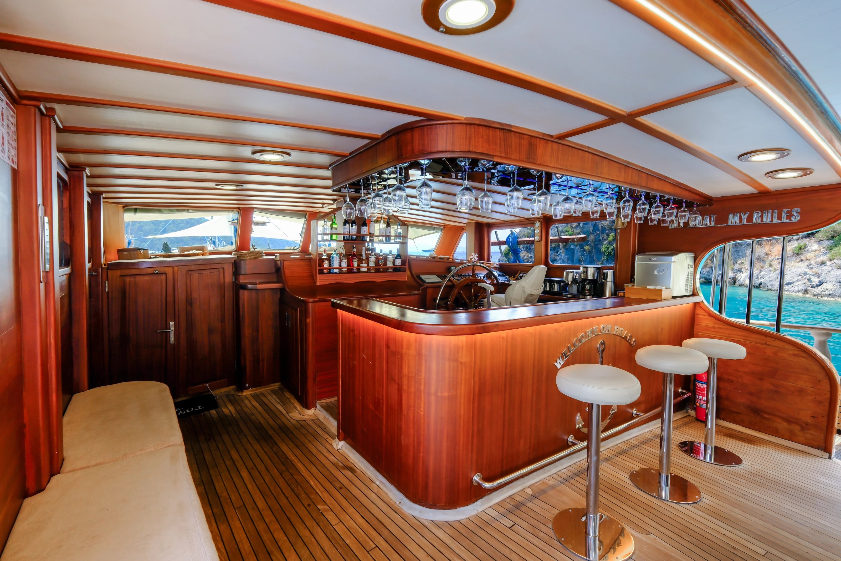 Die stilvolle Bar im Deckshaus der Larin Su mit Barhockern, Mahagoniholz und Blick aufs Steuerrad.