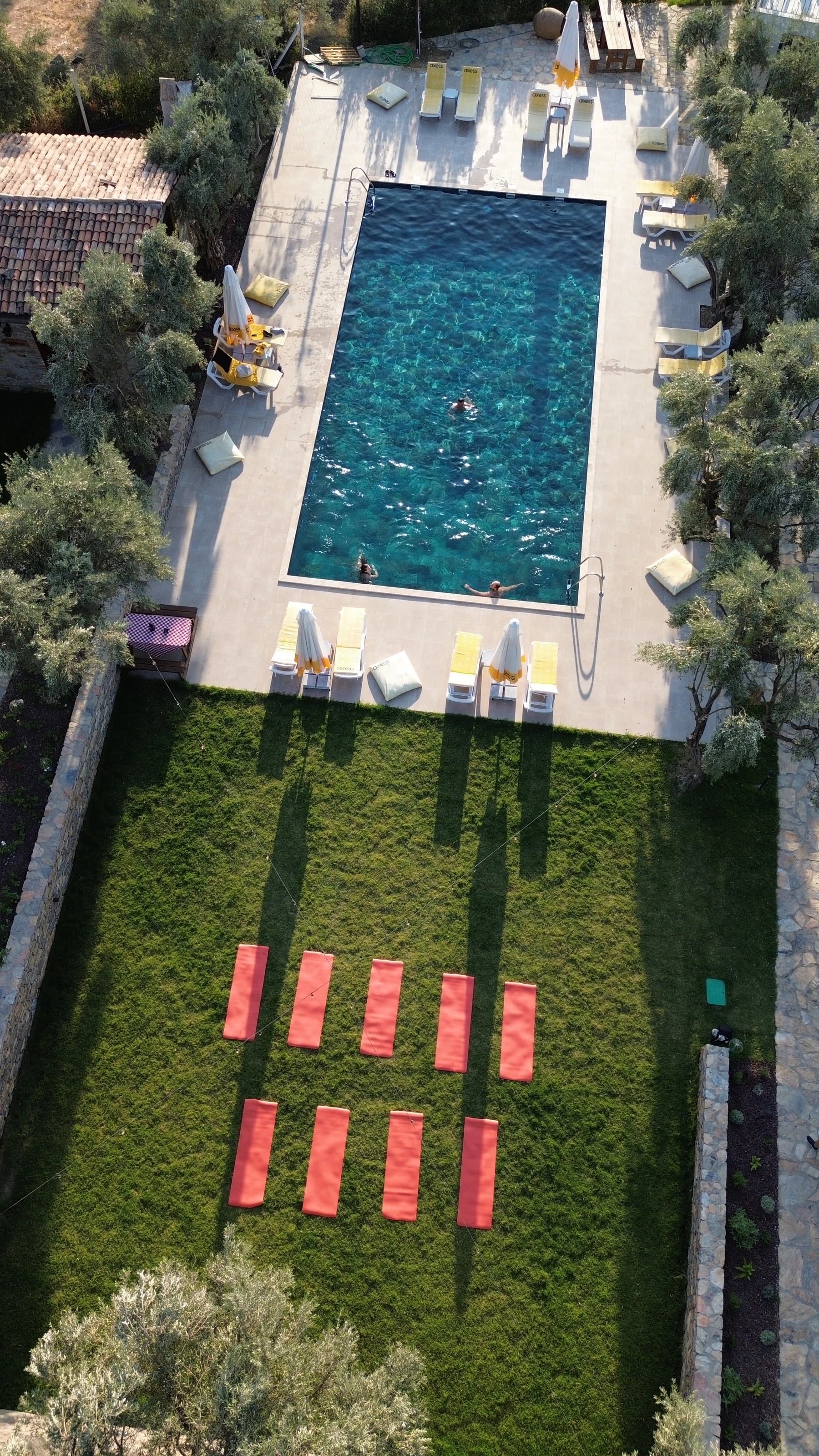 Pool mit Liegen und roten Yogamatten auf der Rasenfläche.
