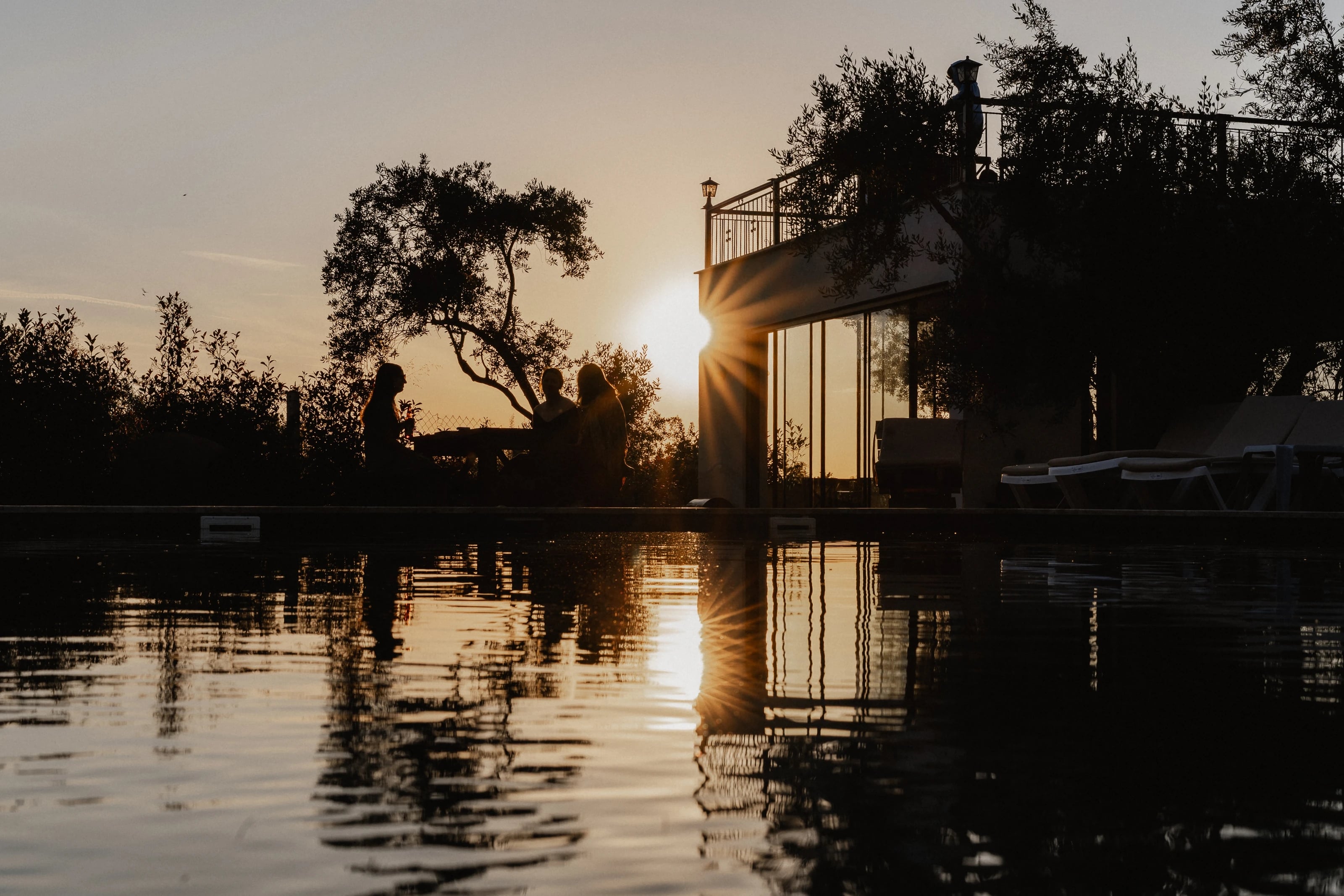 Sonnenuntergang am Pool mit Blick auf das beleuchtete Haupthaus.