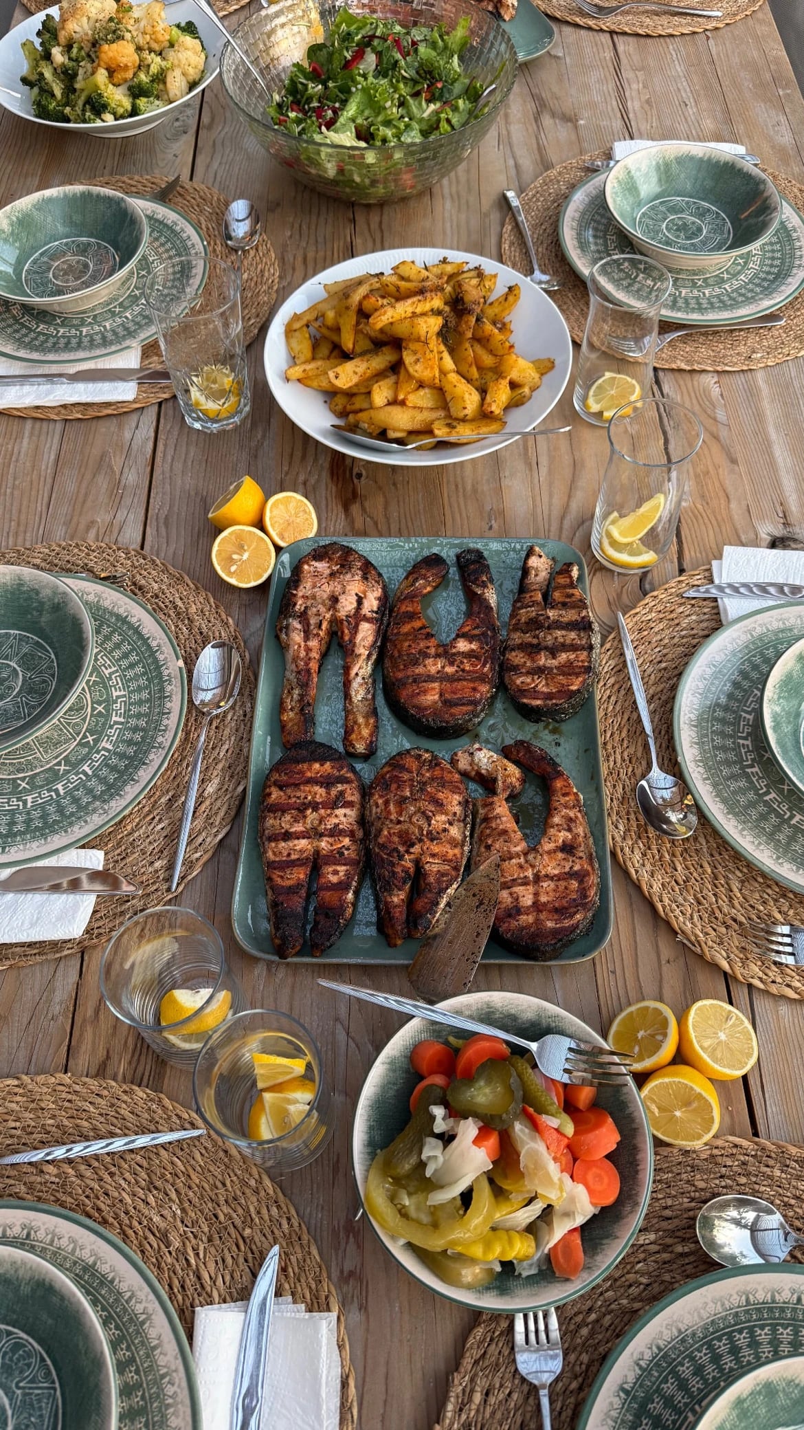 Gegrillter Fisch, Pommes und Beilagen auf der gedeckten Tafel bei einem vergangenen Retreat