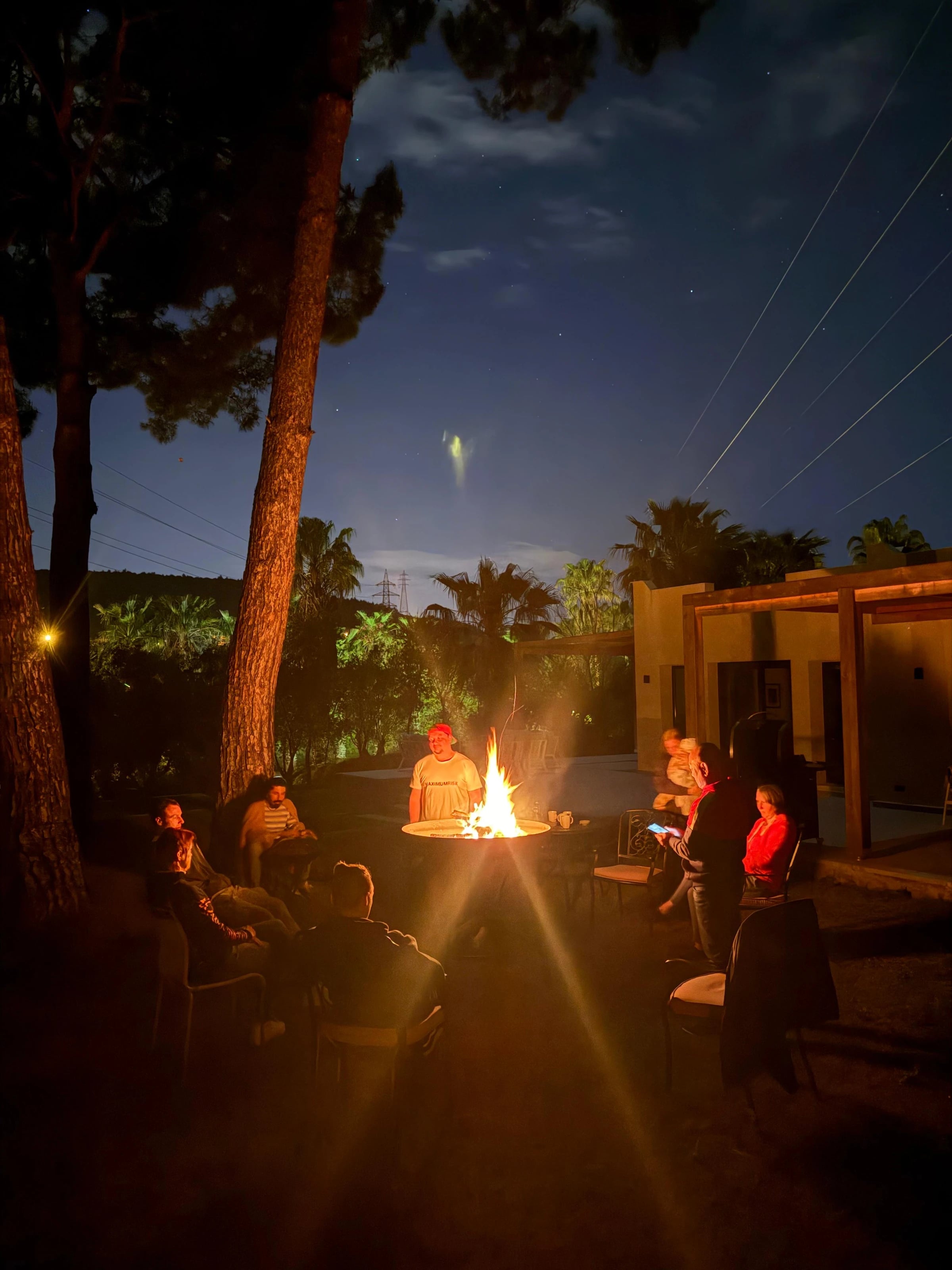 Lagerfeuer am Abend vor dem beleuchteten Anwesen