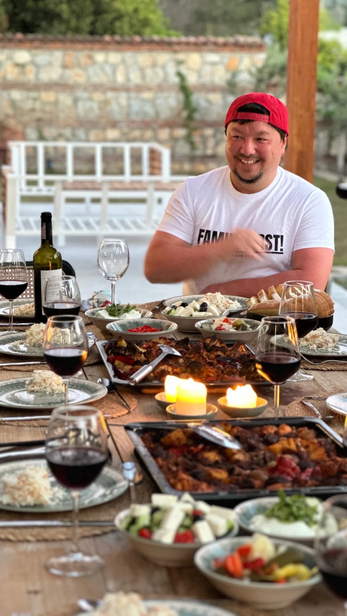 Teilnehmer lacht am reich gedeckten Tisch mit Mezze und Wein