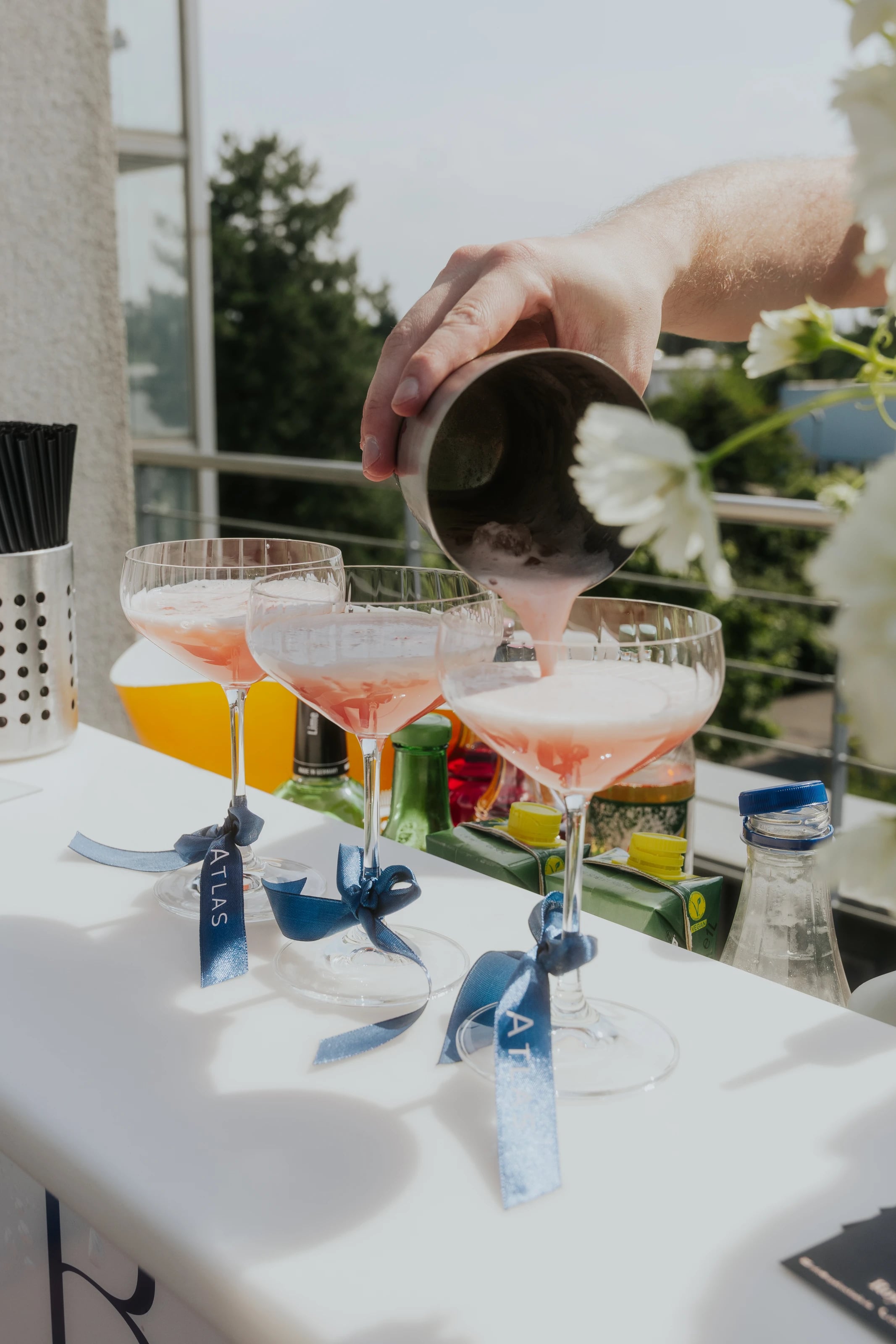 An der Außenbar wird ein rosa Cocktail in bänderverzierte Gläser gegossen.