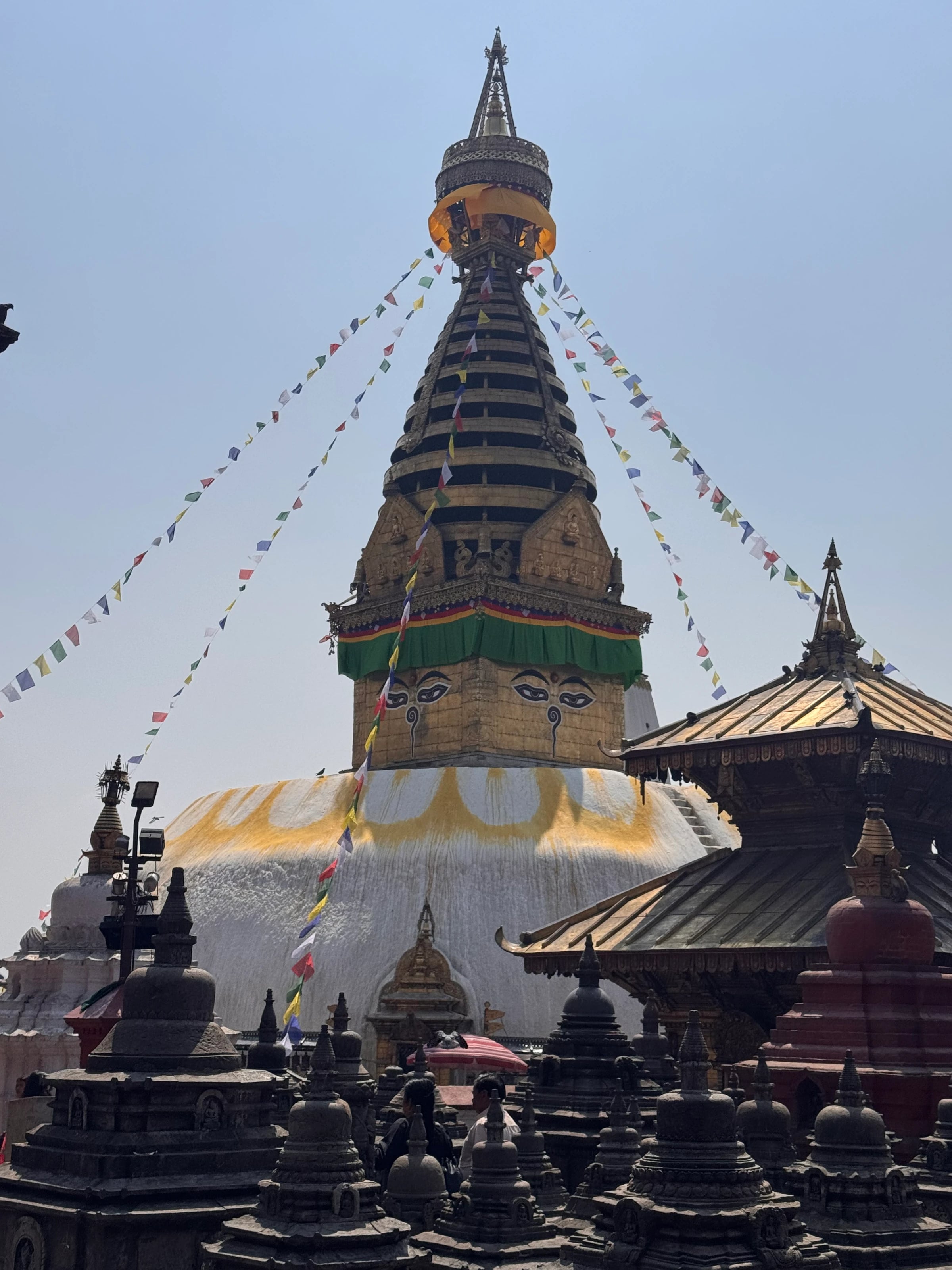Die gemalten Buddha-Augen an der goldenen Turmspitze der Swayambhunath-Stupa mit Gebetsfahnen.