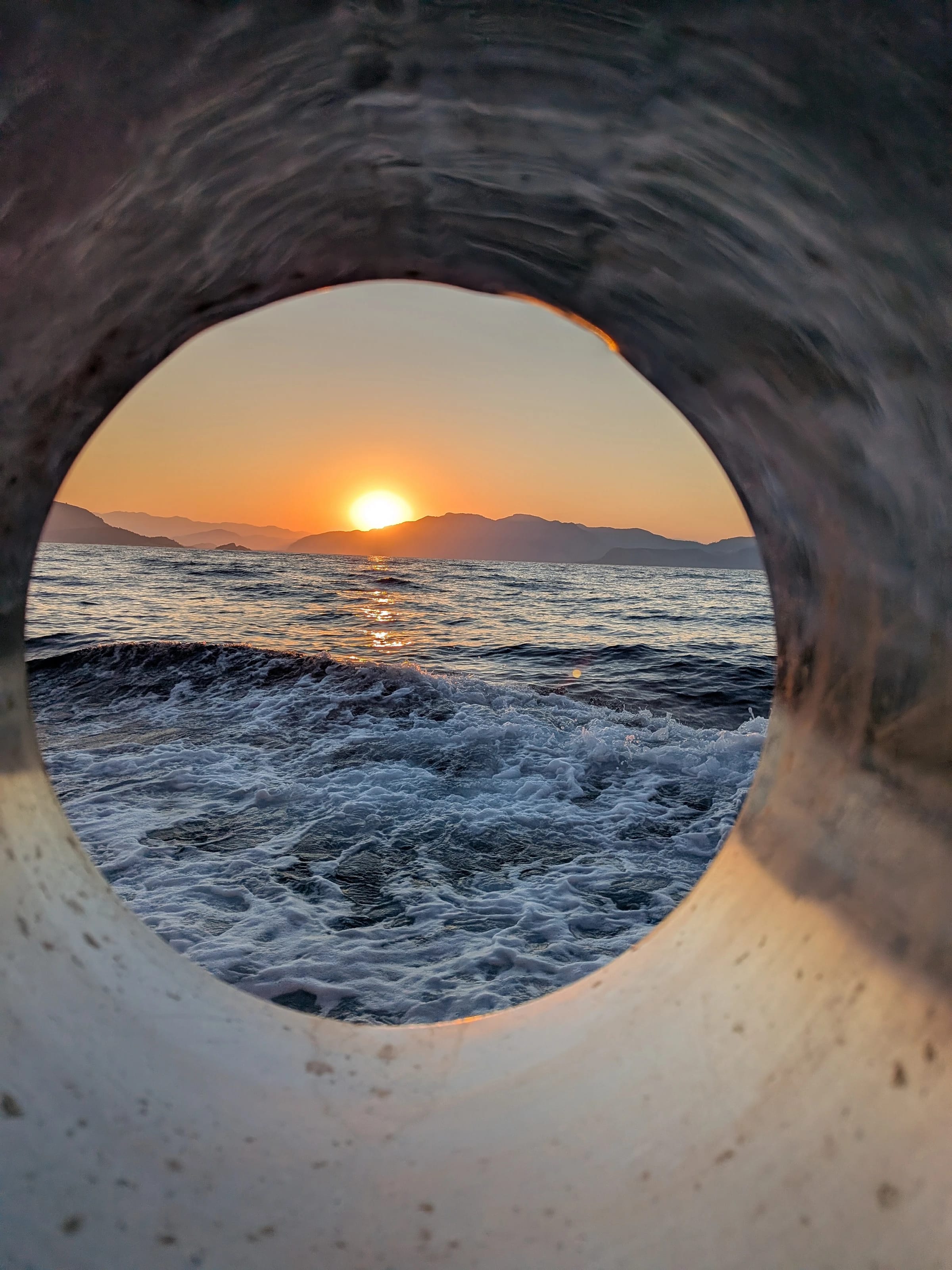 Sonnenaufgang über dem Meer, fotografiert durch ein Bullauge