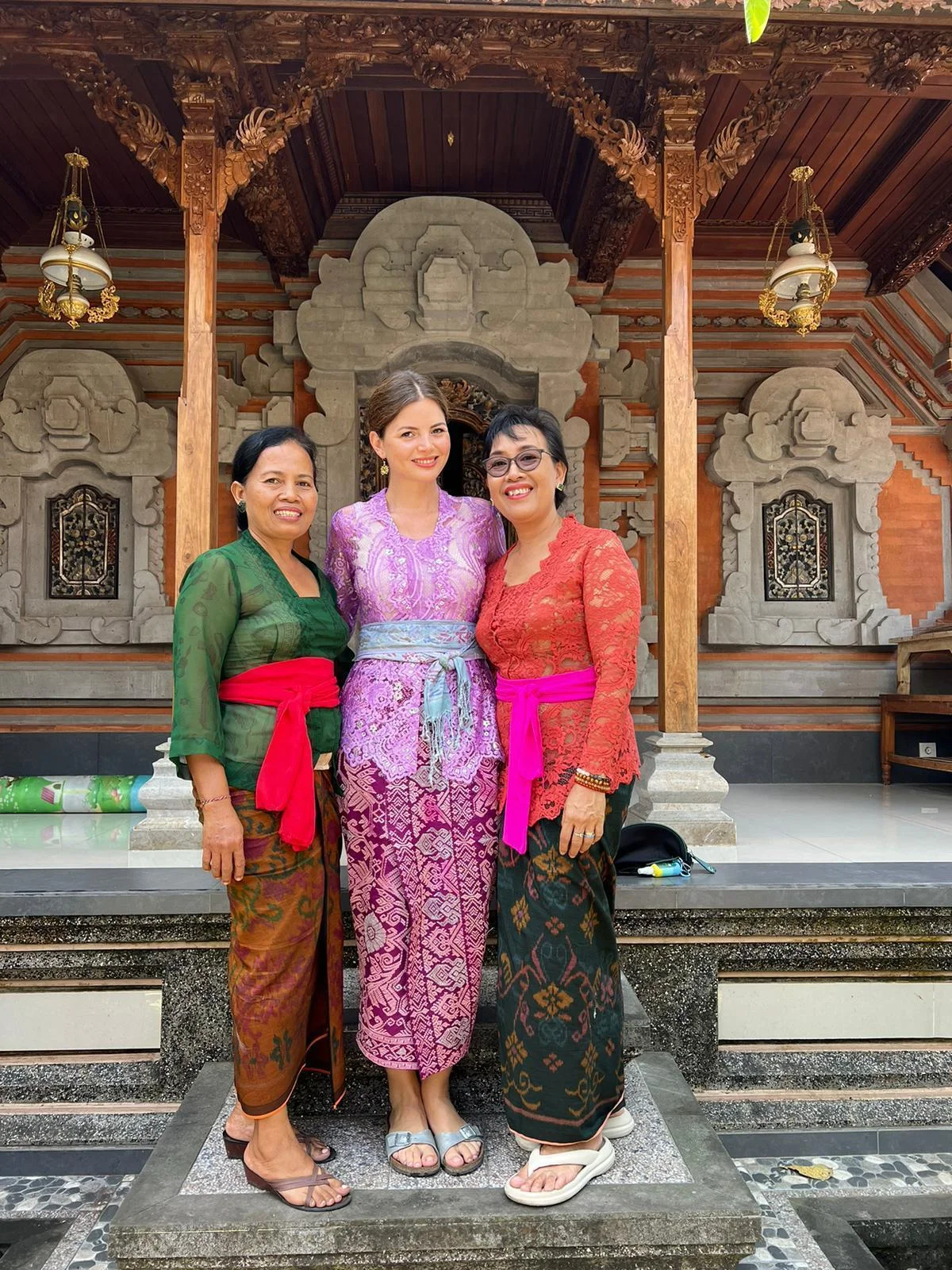 Selin in traditioneller balinesischer Tracht mit zwei einheimischen Frauen an einem Tempel
