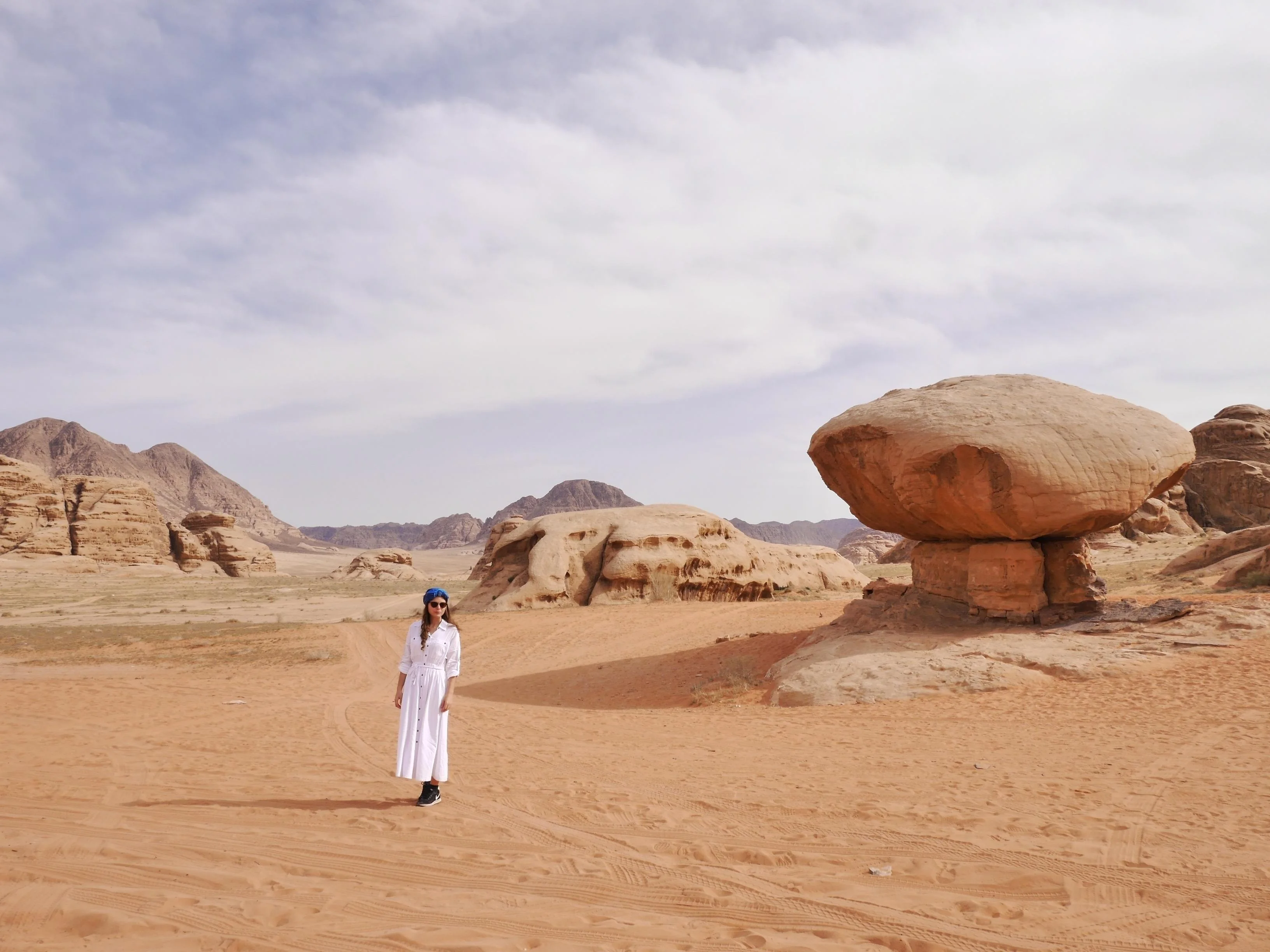 Selin im weißen Kleid an einem Felsen in der Wadi Rum Wüste